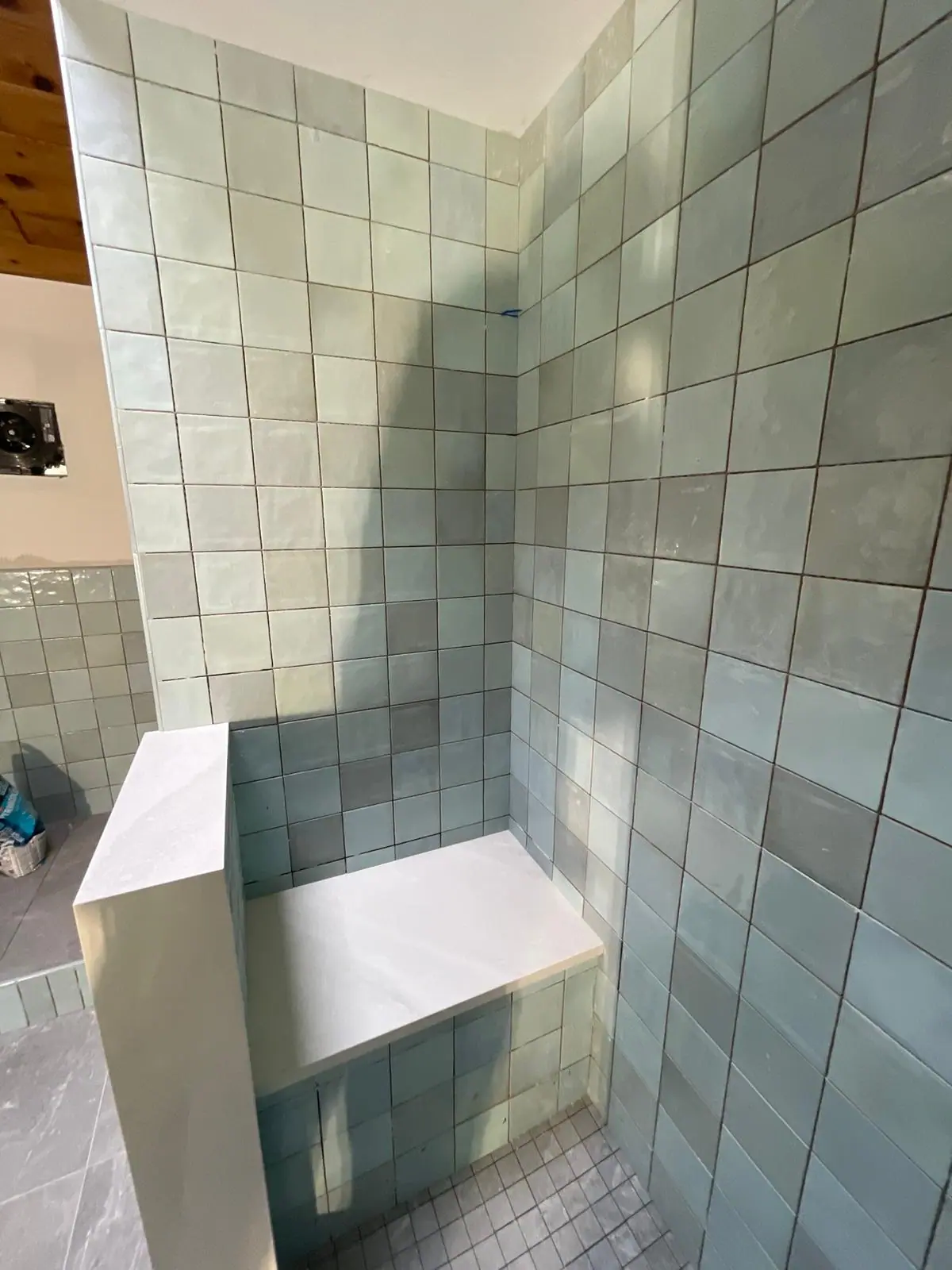 Pale green square tile shower with a tiled bench and a white cap