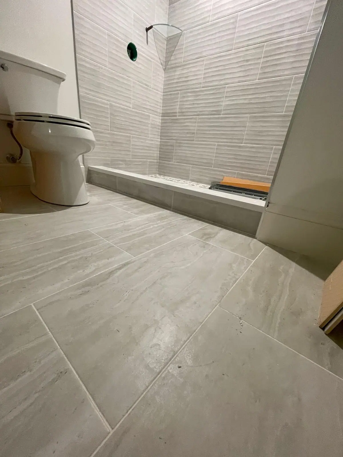 Bathroom floor in large-format light gray tile laid in a straight pattern
