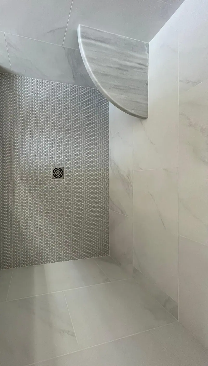 Shower with white marble-look wall tile, a mosaic accent strip and a stone corner shelf