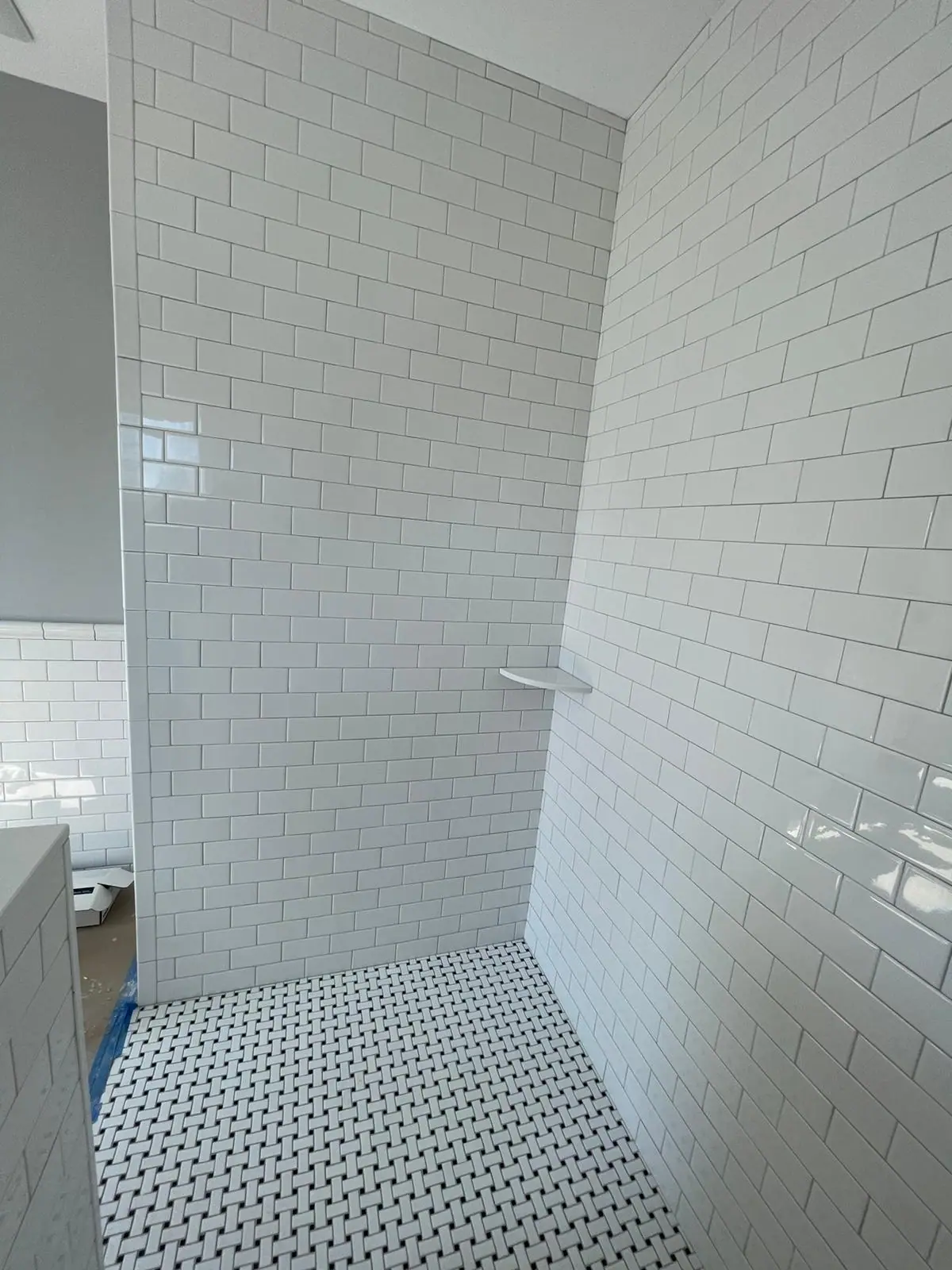 White subway tile shower with a black and white dot mosaic floor
